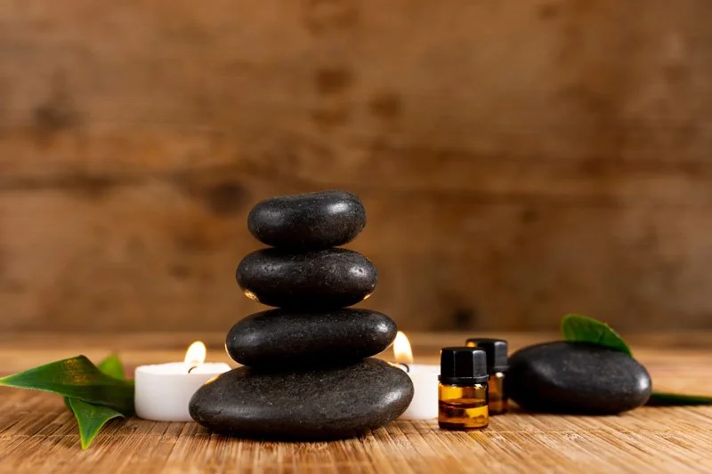 Elementos de bienestar: piedras de masaje, aceites esenciales y vela en Inhala Massage & Wellness Center en Sevilla